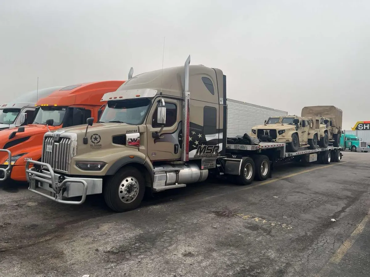 MSR military-wrapped truck hauling tactical vehicles on a flatbed